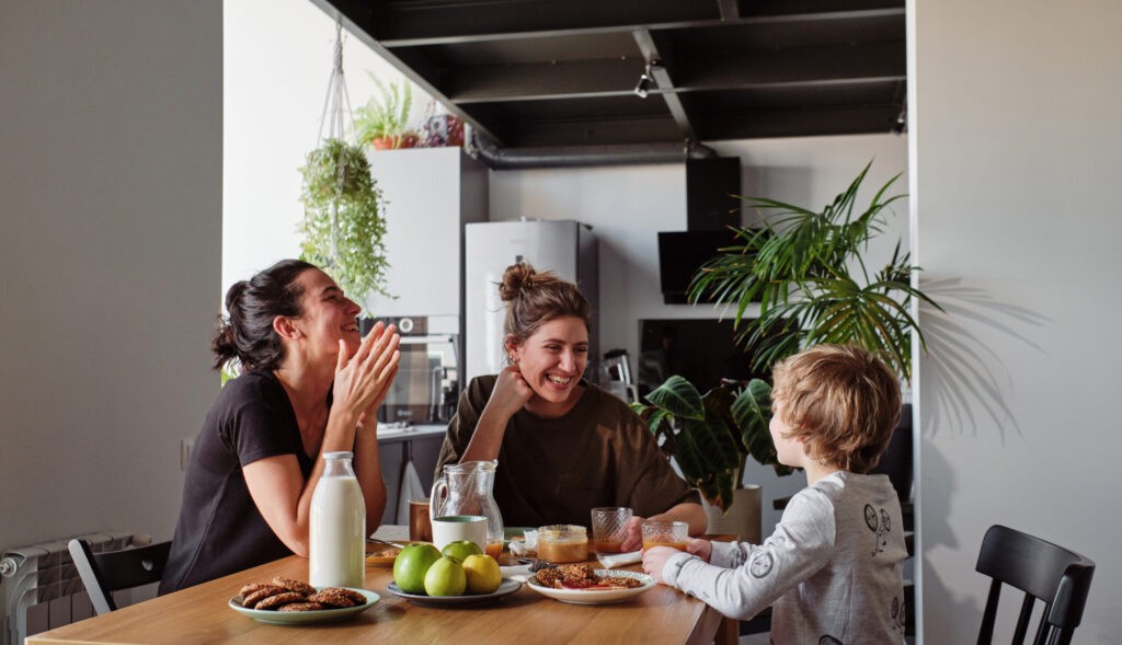Happy LGBTQ+ family laughing during breakfast